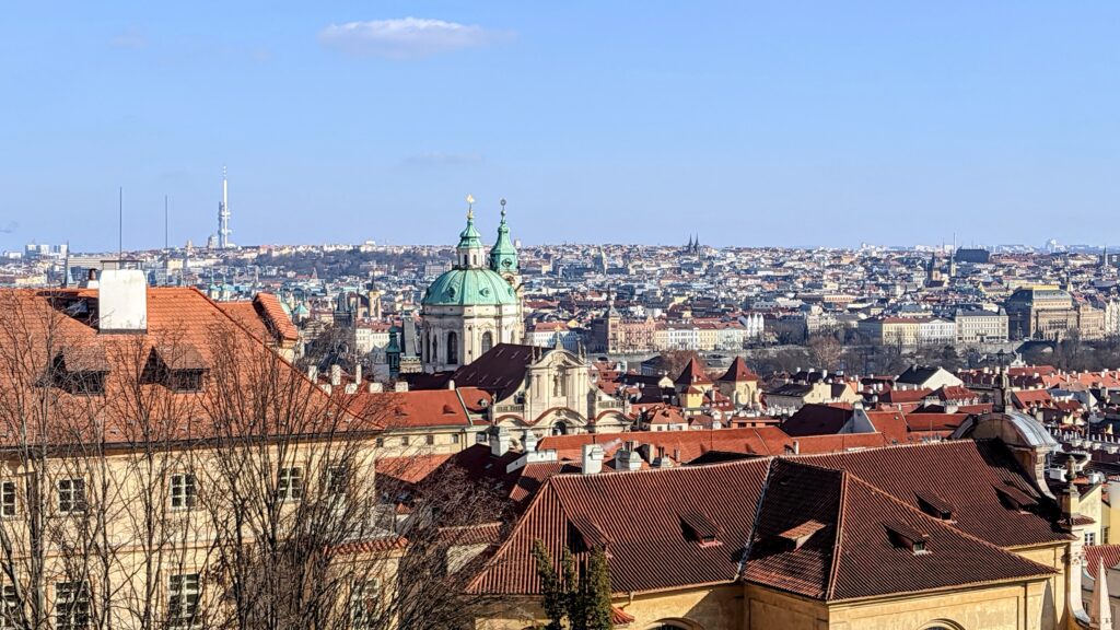 Panoramic view of Prague with St. Nicholas Church and red rooftops on a clear winter day, capturing the peaceful charm of Europe’s low season.