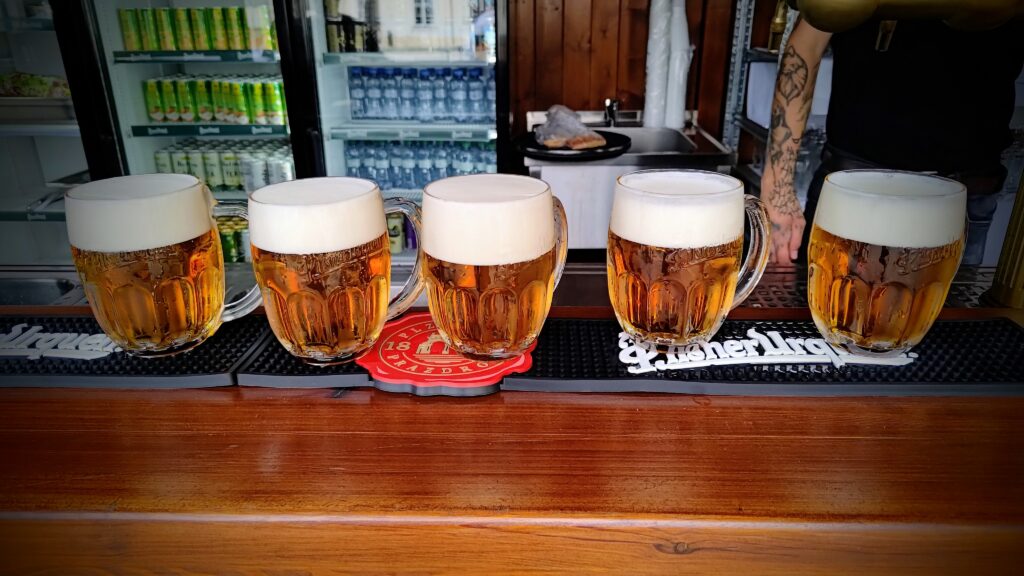Five mugs of freshly poured Pilsner Urquell beer in a traditional Czech pub, part of a local travel experience with private guide Europe With Zuzana.