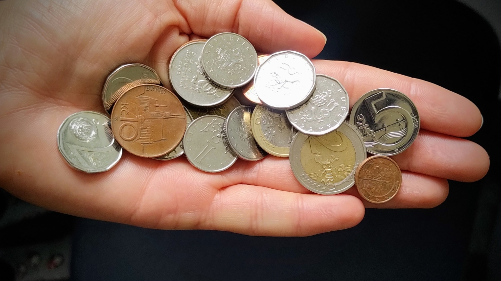 Hand holding Czech and euro coins, representing practical travel tips about currency and cash use in Czechia.